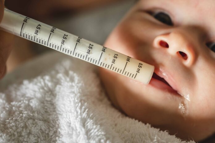 Close up on small caucasian baby four months old and hand of unk Antibiotic side effects children