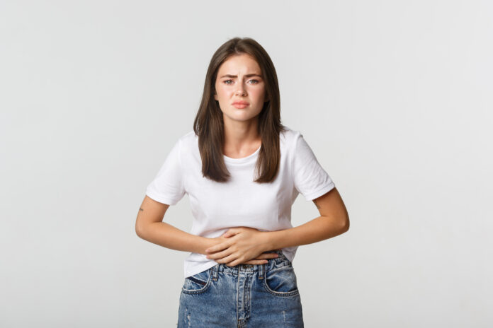Woman having stomach ache, bending and holding hands on belly, discomfort from menstrual cramps. Girl feeling nauseous Gut Bacteria and Amino Acid Imbalance Linked to Higher Miscarriage Risk in Women with PCOS